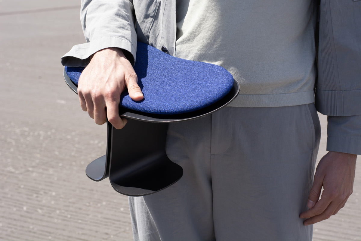 The seat carried in one hand, at the hip